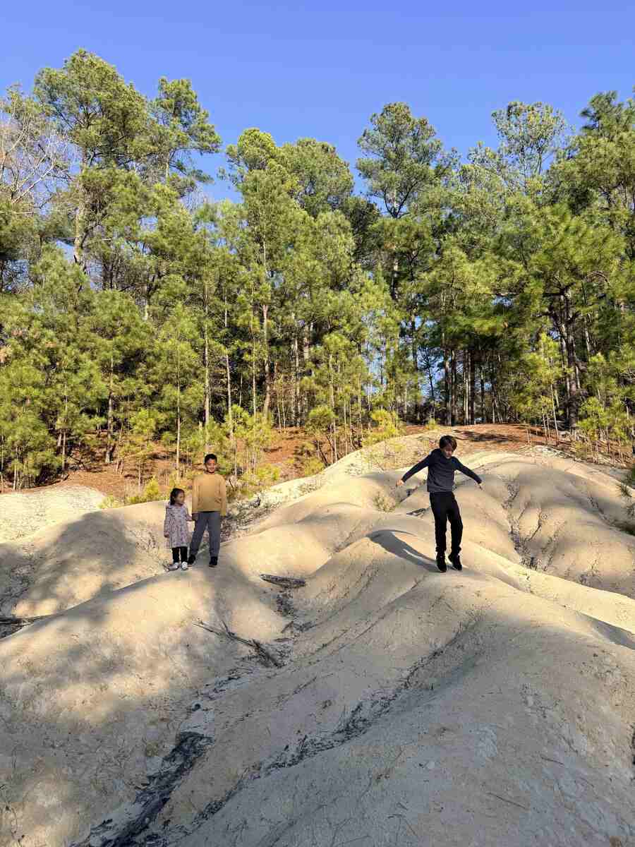 Three kids playing on white rocks or sand